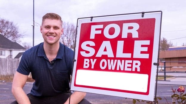 Man standing next to for sale by owner sign