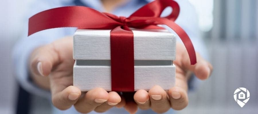 Hands holding a gift box with red ribbon for real estate client appreciation.
