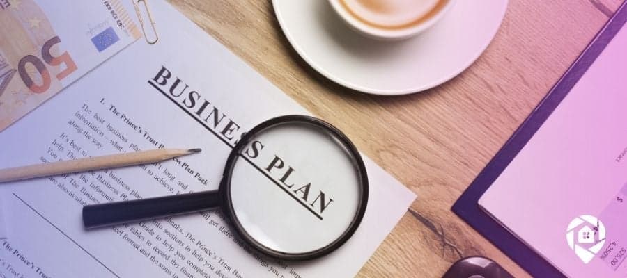 A business plan on a paper with a magnifying glass over it.