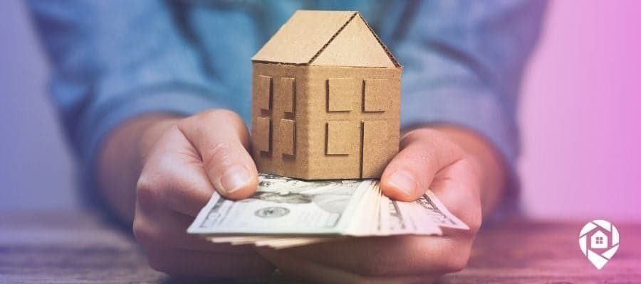 A rental owner with money fanned out under a cardboard house symbolizing the taxes they pay on rentals.