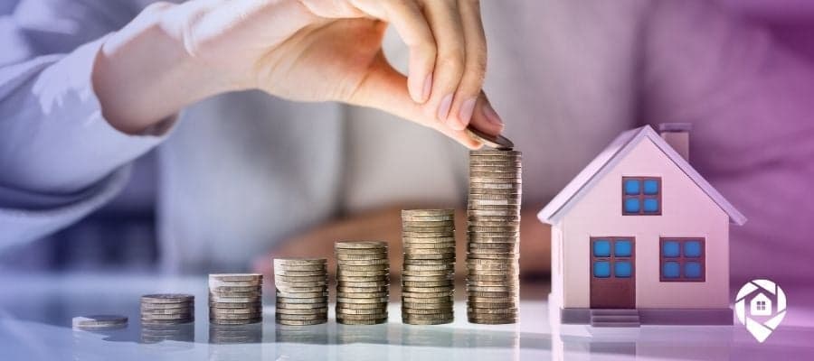 Money stacks next to a house for property investment