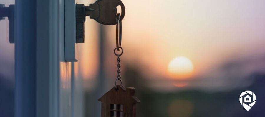 Key with house-shaped keychain in door at sunset – Real Estate Wholesaling Success