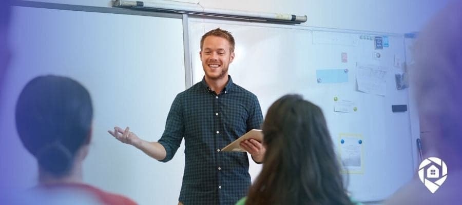 Smiling teacher presenting to a classroom, representing starting a real estate wholesaling business while working full-time.