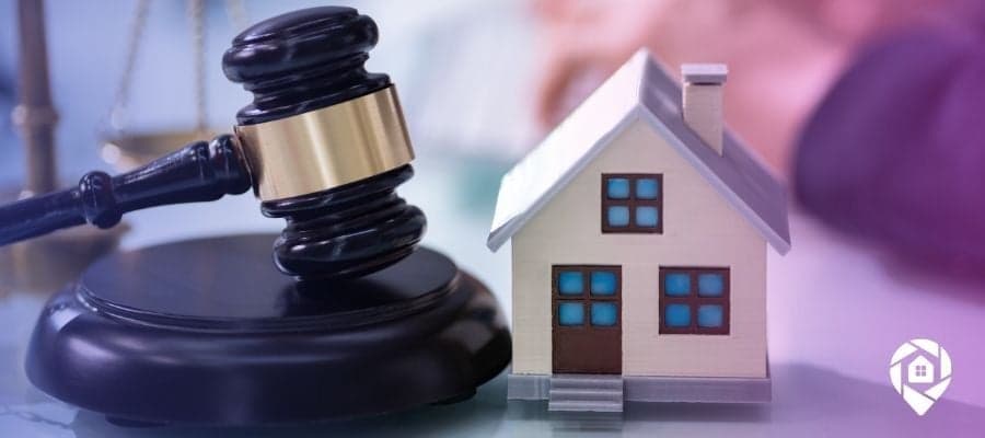 A court gavel next to a house on a table to symbolize legal troubles and foreclosed homes.