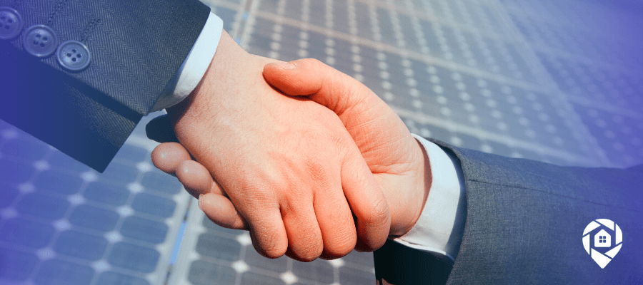Solar professionals shaking hands over rooftop panels after closing more solar deals with debt consolidation.