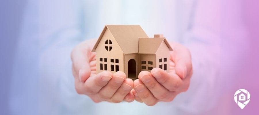 Hand holding a cardboard house or property to be the image for lien search on a property.