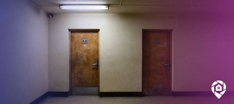 Two dirty apartment doors in a poorly lit hallway