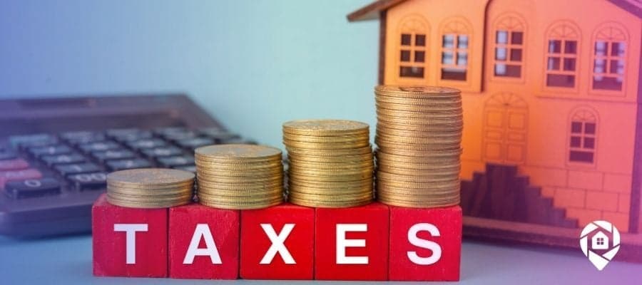 Taxes spelled out on blocks in front of a house and calculator on a desk