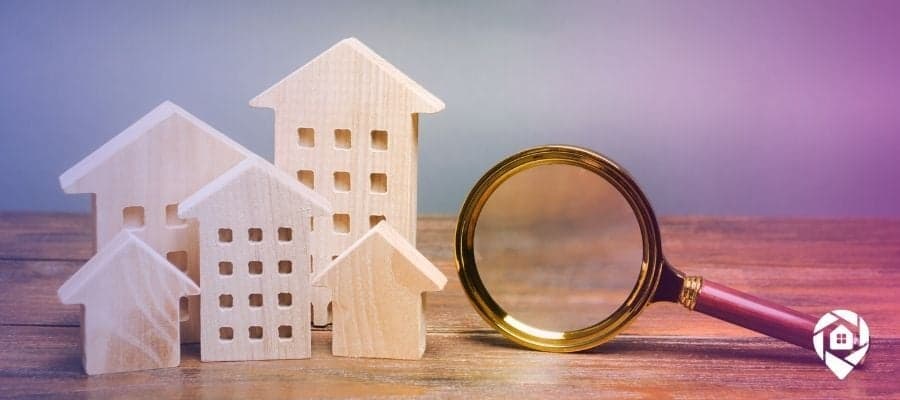 A magnifying glass on a table next to wooden houses searching for property liens.