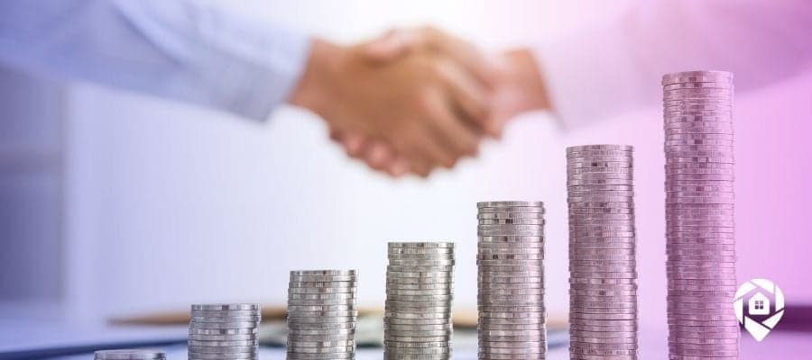 Picture of coin stacks in front of two people shaking hands in the background for how to fund real estate deals.
