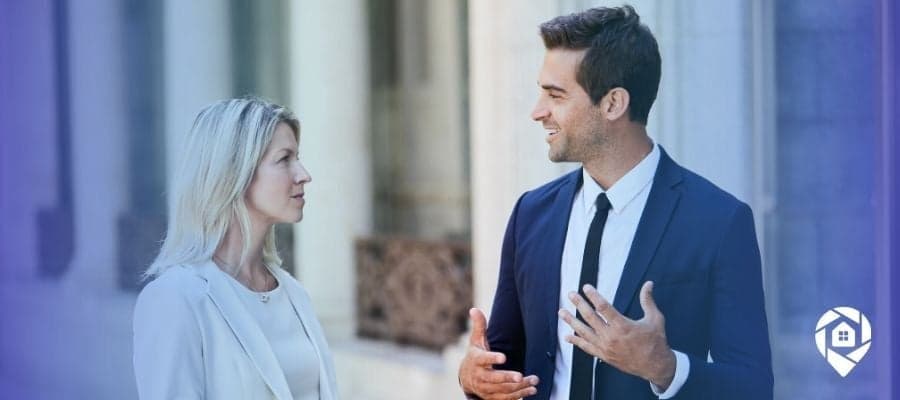 Real estate wholesaler confidently discussing negotiation strategy with a client outside a property.