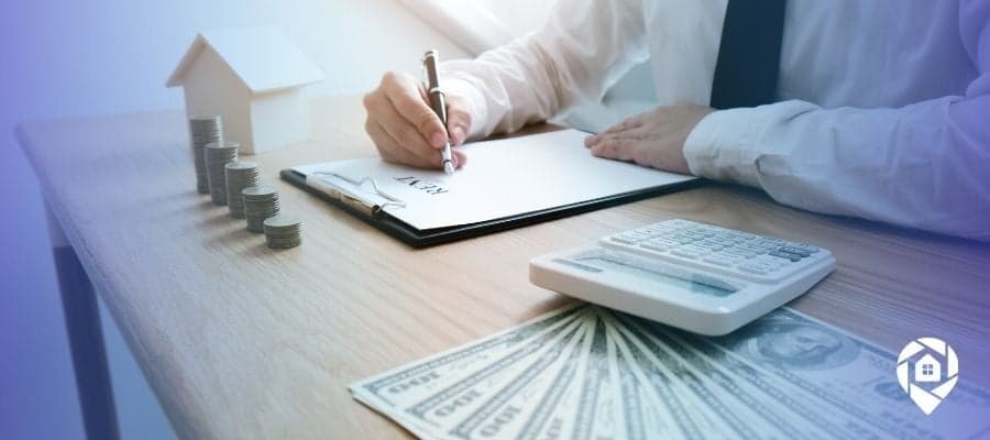 Investor signing real estate agreement with money, calculator, and property model on desk for passive income strategy.