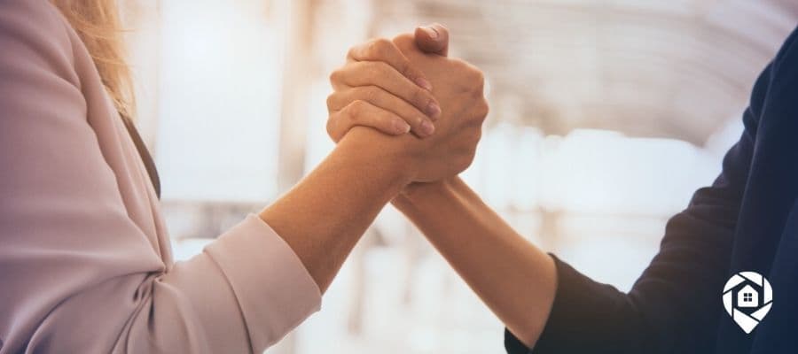 Two real estate professionals shaking hands on a win-win deal.