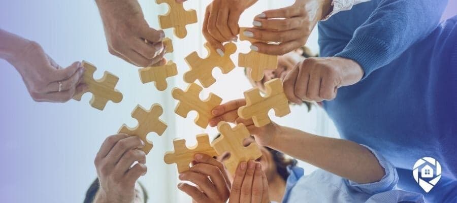 Real estate team collaboration concept – hands connecting puzzle pieces, symbolizing teamwork and strategy in real estate investing.