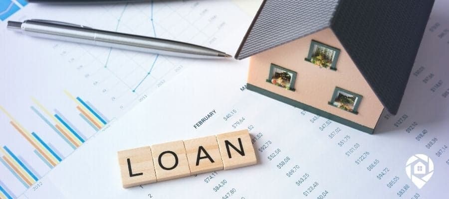 Model house and loan documents representing seller financing in real estate investing.