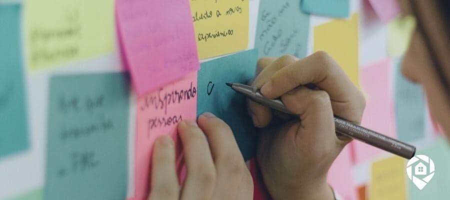 Person writing on colorful sticky notes on a wall, brainstorming ideas.