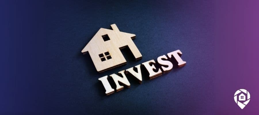 A cut out of a wood house with the word invest underneath it to symbolize house investments in a downturn economy.